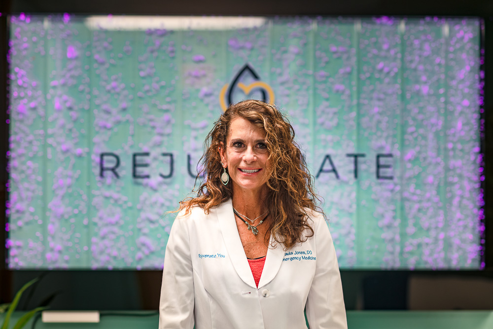 Dr. Paula Jones in front of a Rejuvenate You sign.