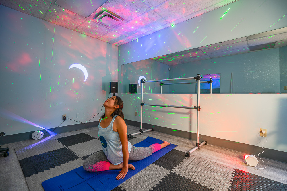 A woman stretching on a yoga mat before her Barre Above Pilates exercises.