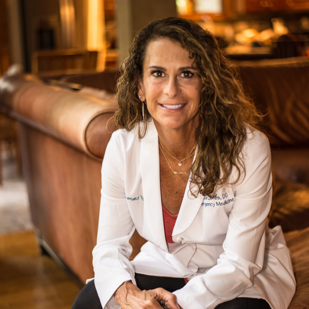 Holistic care physician Dr. Paula Jones sitting and smiling in a lab coat.