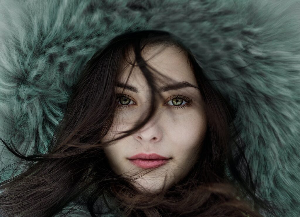 A brunette woman in a fur hood with beautiful skin.