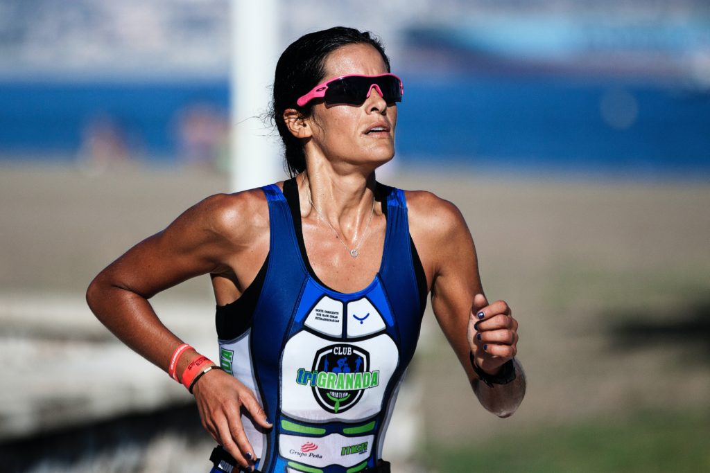 Female long-distance runner for Granada in blue racing tank and pink sunglasses.