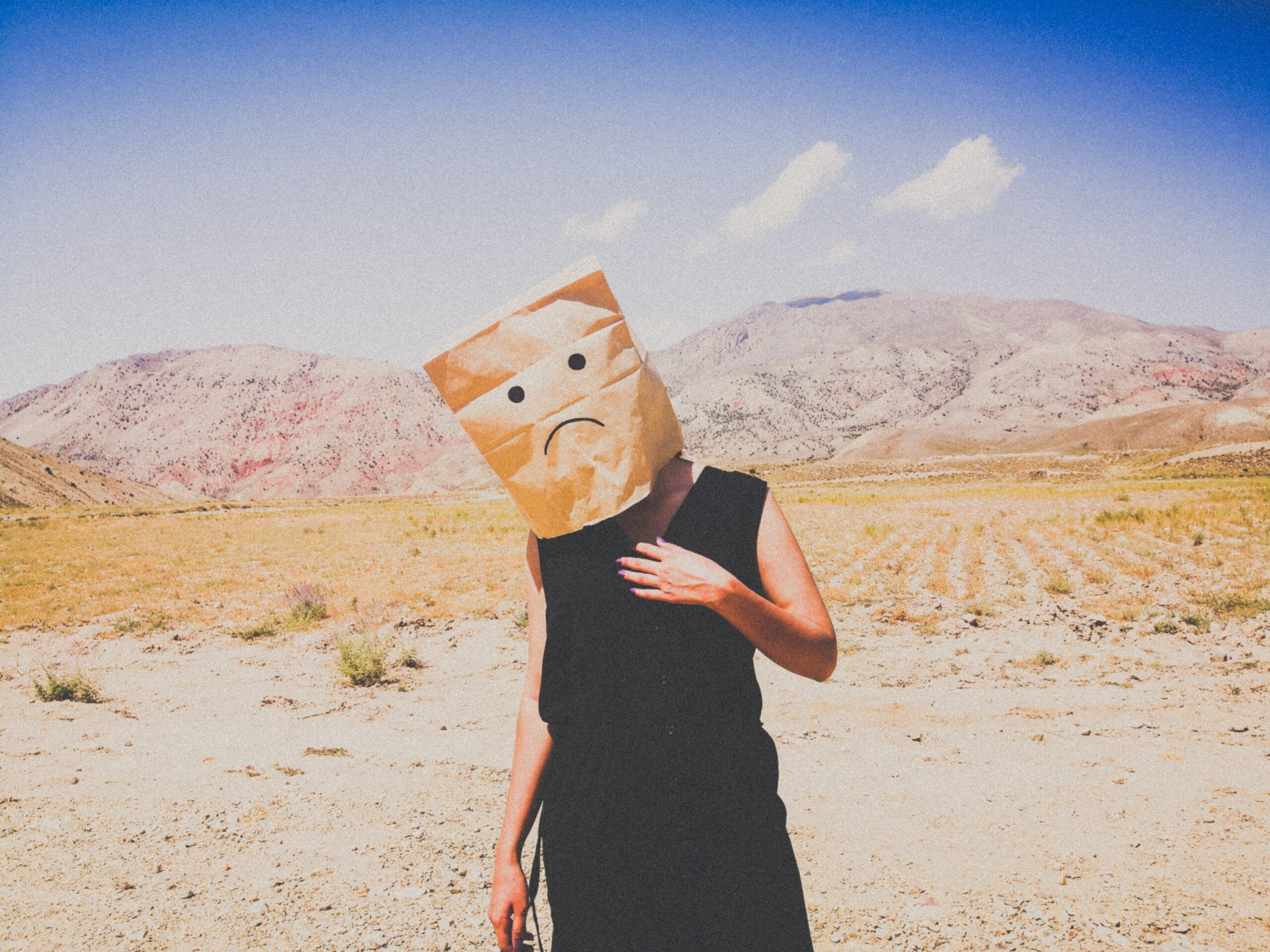 A man with bag and a sad face on his head in the desert.