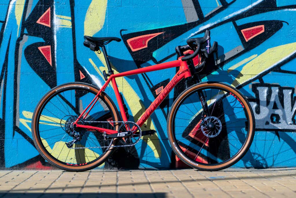 A red race bicycle against an city wall spray painted blue and yellow.