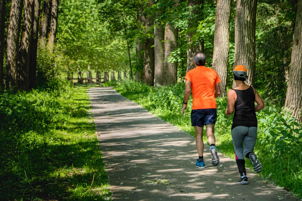 A middle-aged couple going for a run on a trail.