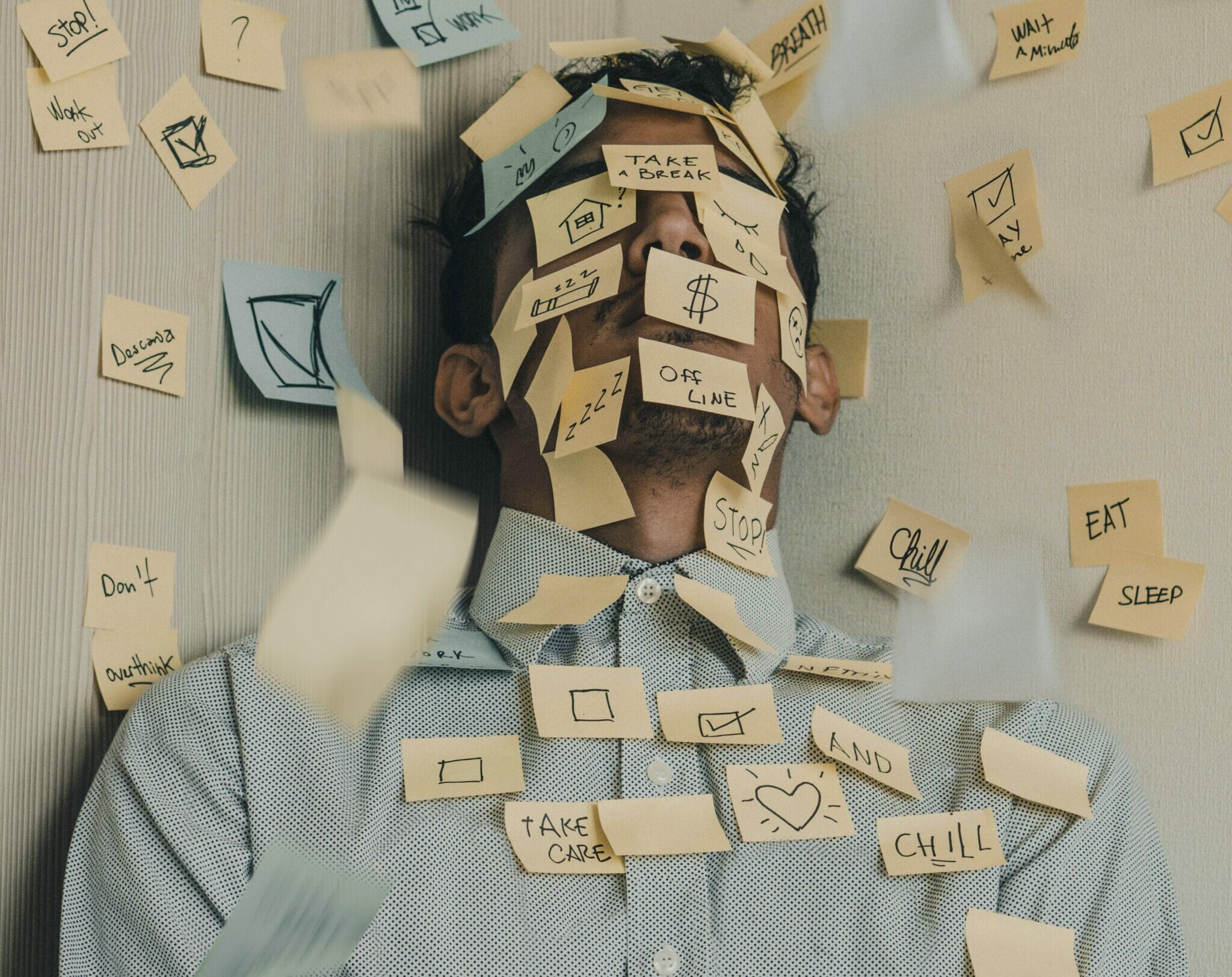 A man overwhelmed by stress with post-it notes all over his body.