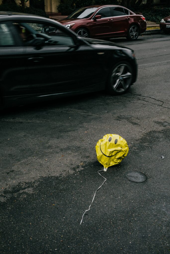 A smiley-faced balloon on the streets of a city.