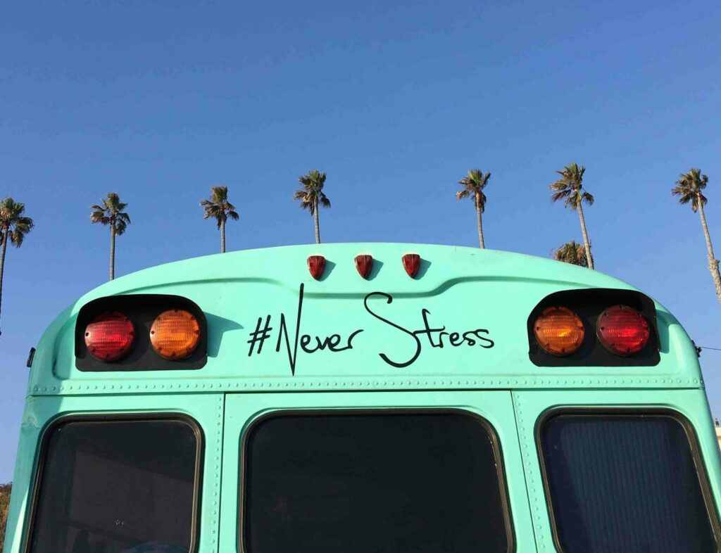 A turquoise school bus with the words Never Stress on it.