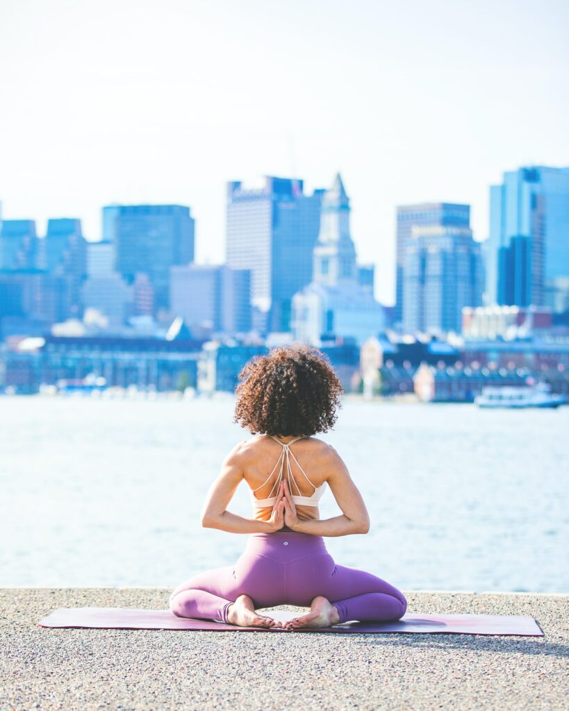 A woman practicing yoga, one of the most fun stress relieving activities, across the river from Boston.