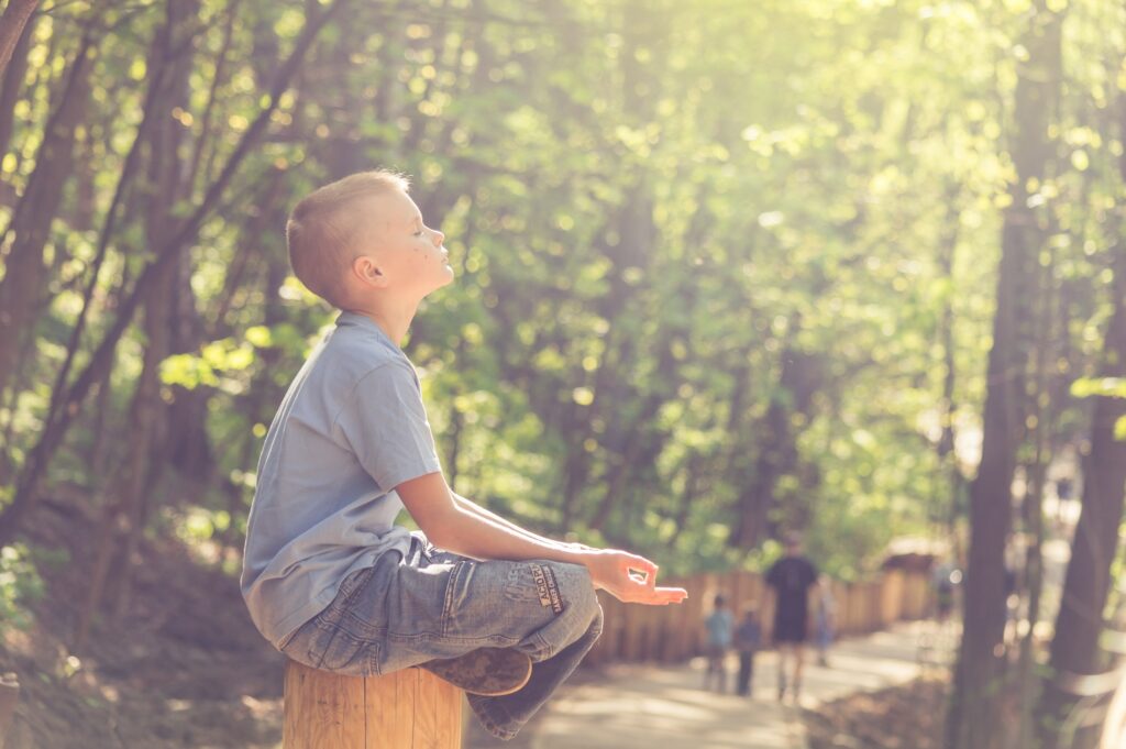 A young boy soaking up some vitamin D while meditating in the sunshine.