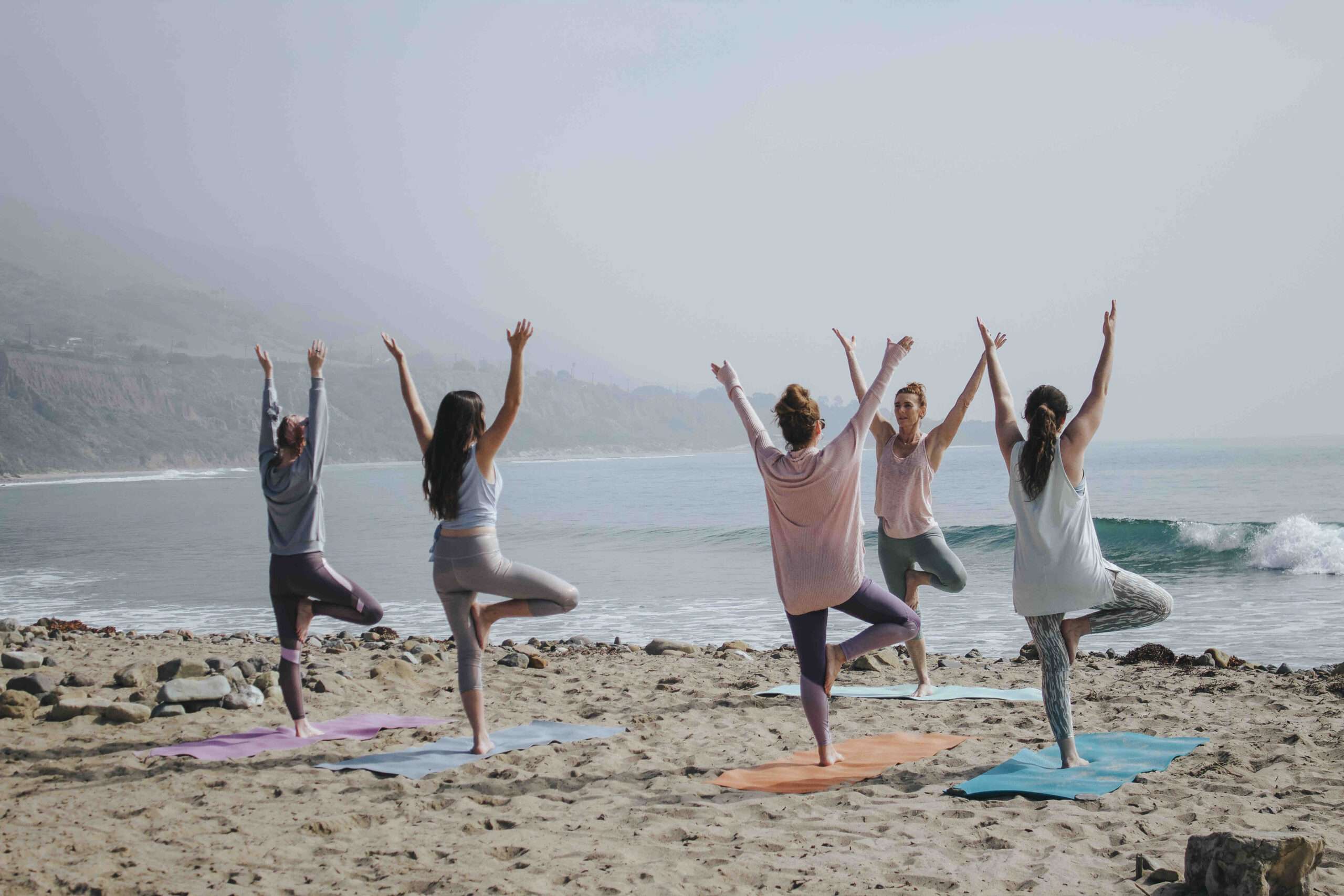 A group of women doing yoga on a beach.