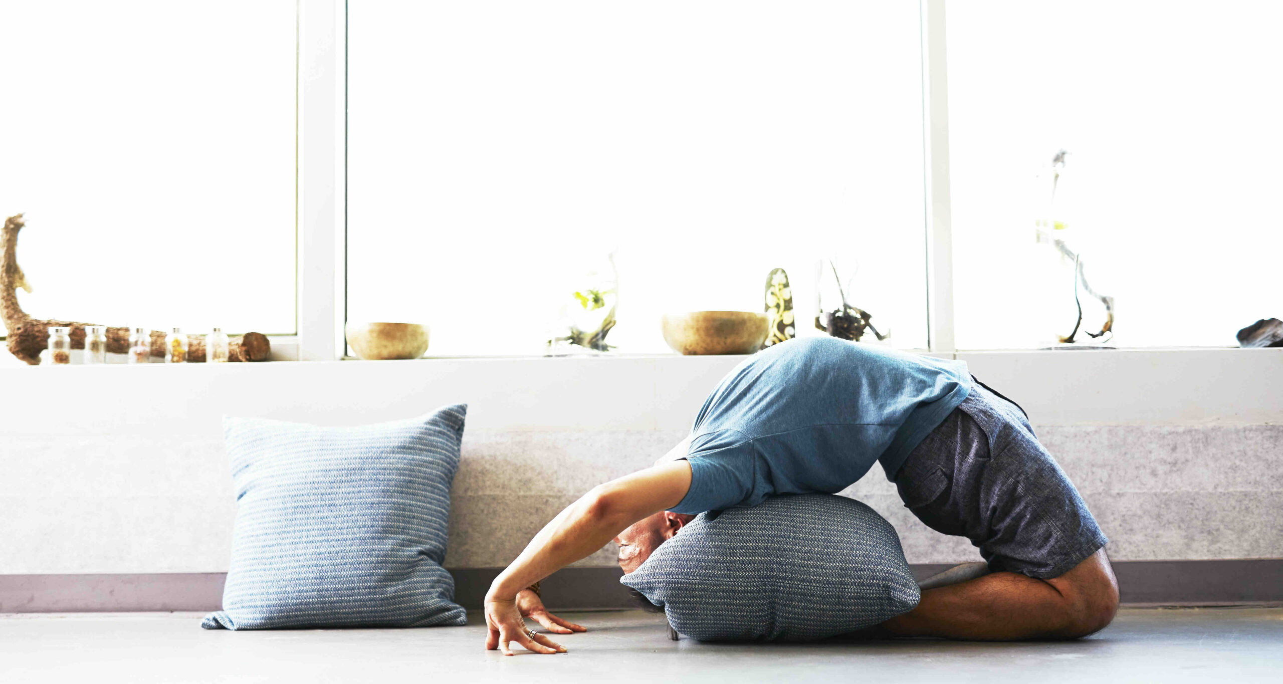 A woman doing a yogic back bend on a pillow.