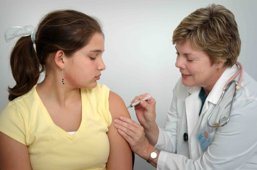 A young girl getting an injection from a doctor.