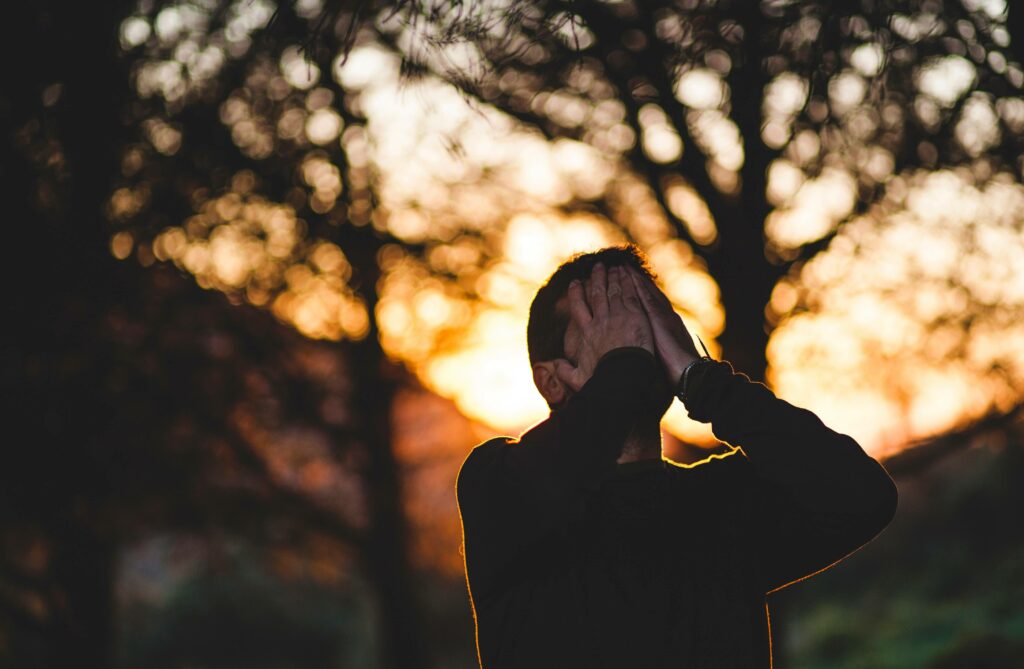 A stressed man with his hands on his face.