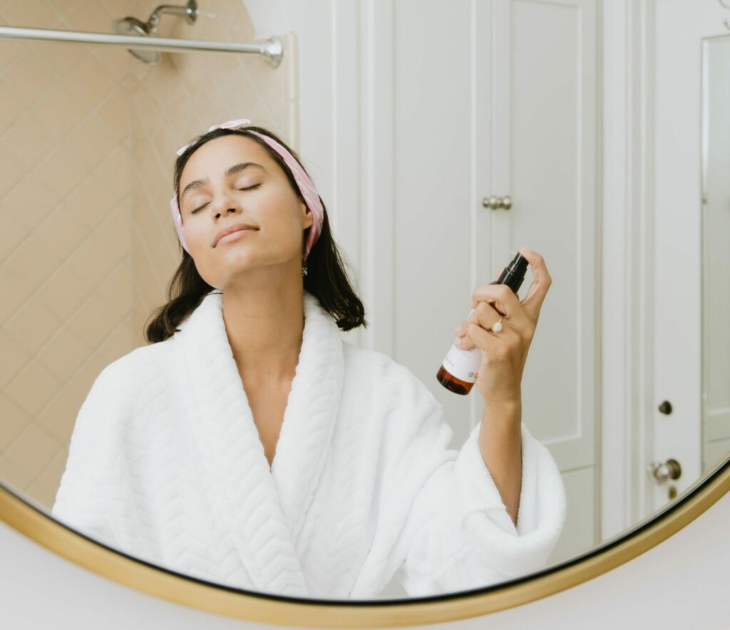 A woman spraying a skincare product with nutrients and vitamins for skin health.